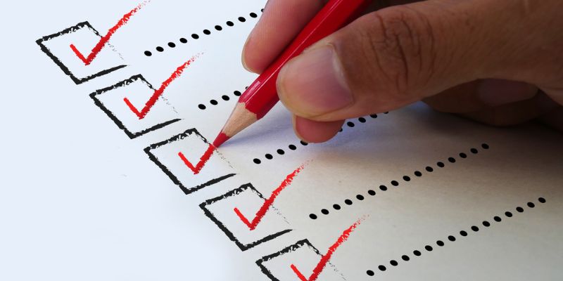 Person checking off items with a red pencil on a to-do list.