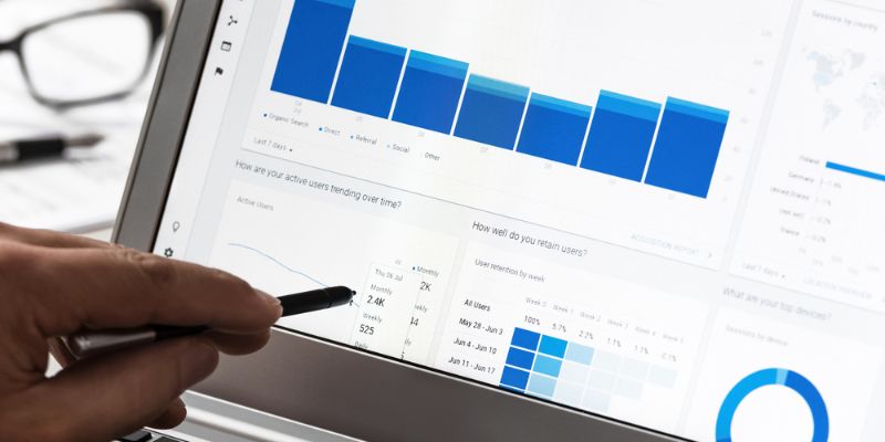 Close-up of hand pointing at digital analytics dashboard on a laptop.